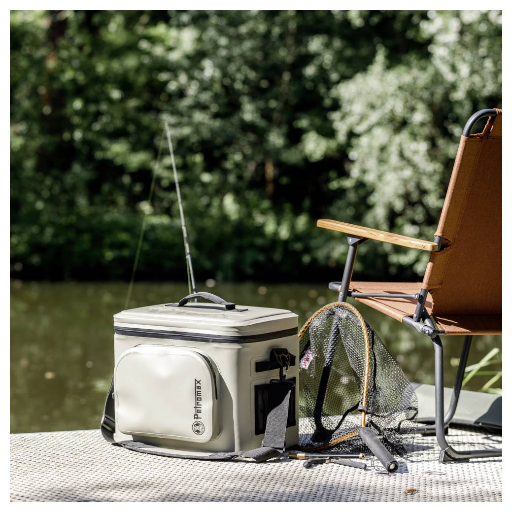Configuration de pêche sur un quai au bord de l'eau, avec une glacière de matériel, un filet d'épuisette, une canne à pêche et une chaise.