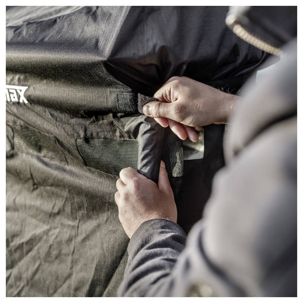 Gros plan des mains fermant la fermeture éclair d'un sac ou d'une housse de matériel en tissu noir avec un logo blanc.