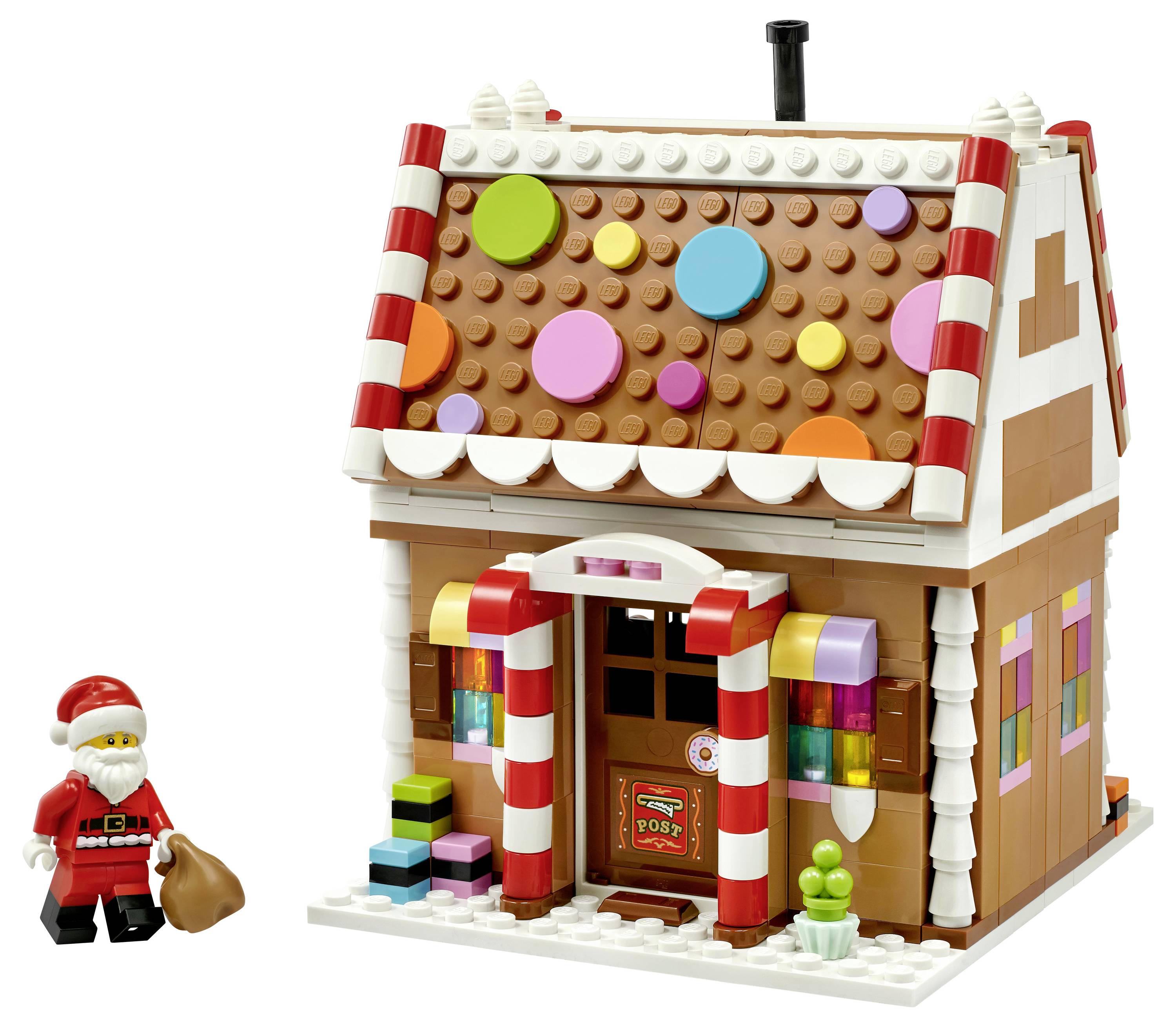 Bureau de poste en pain d'épices LEGO avec des points de toit aux couleurs de bonbons et une figurine LEGO du Père Noël tenant un sac à côté.