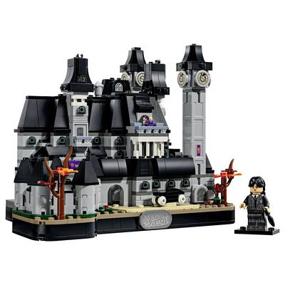 Ensemble de château gothique de style LEGO avec toits noirs, tours et minifigurine, présenté sur un socle d'exposition avec la plaque nominative « Nevermore Academy ».