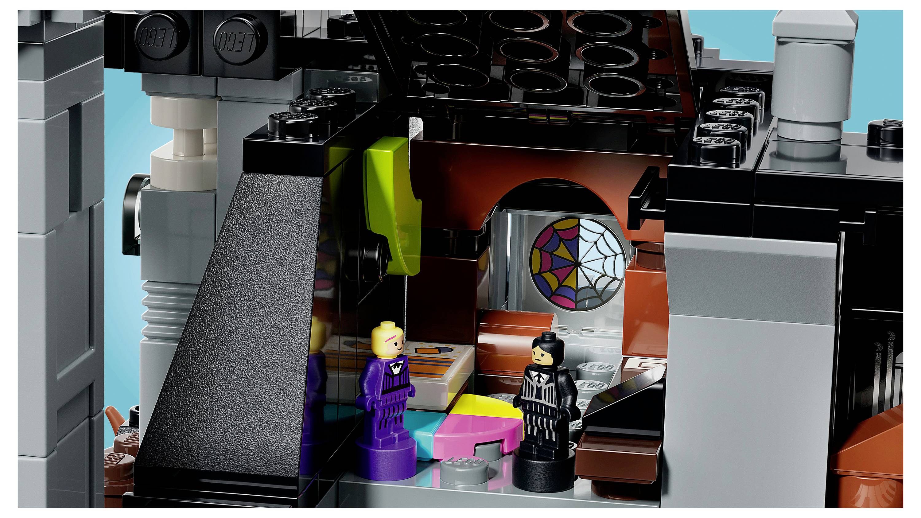 Deux figurines LEGO se tiennent à l'intérieur d'une chambre en forme de château coloré avec une ouverture en vitrail arquée et des accents néon lumineux.