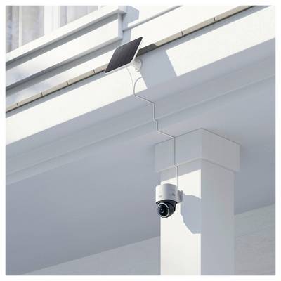 Caméra de sécurité alimentée par énergie solaire montée sur un pilier blanc d'un bâtiment sous un débord de toit.