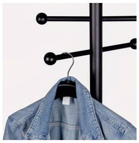 Veste en denim suspendue à un porte-manteau noir avec des crochets ronds sur un fond clair et uni.