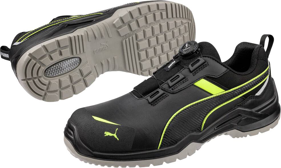 Chaussures de travail de sécurité Puma noires et vert néon, présentées de côté et par la semelle pour mettre en évidence la bande de roulement antidérapante.