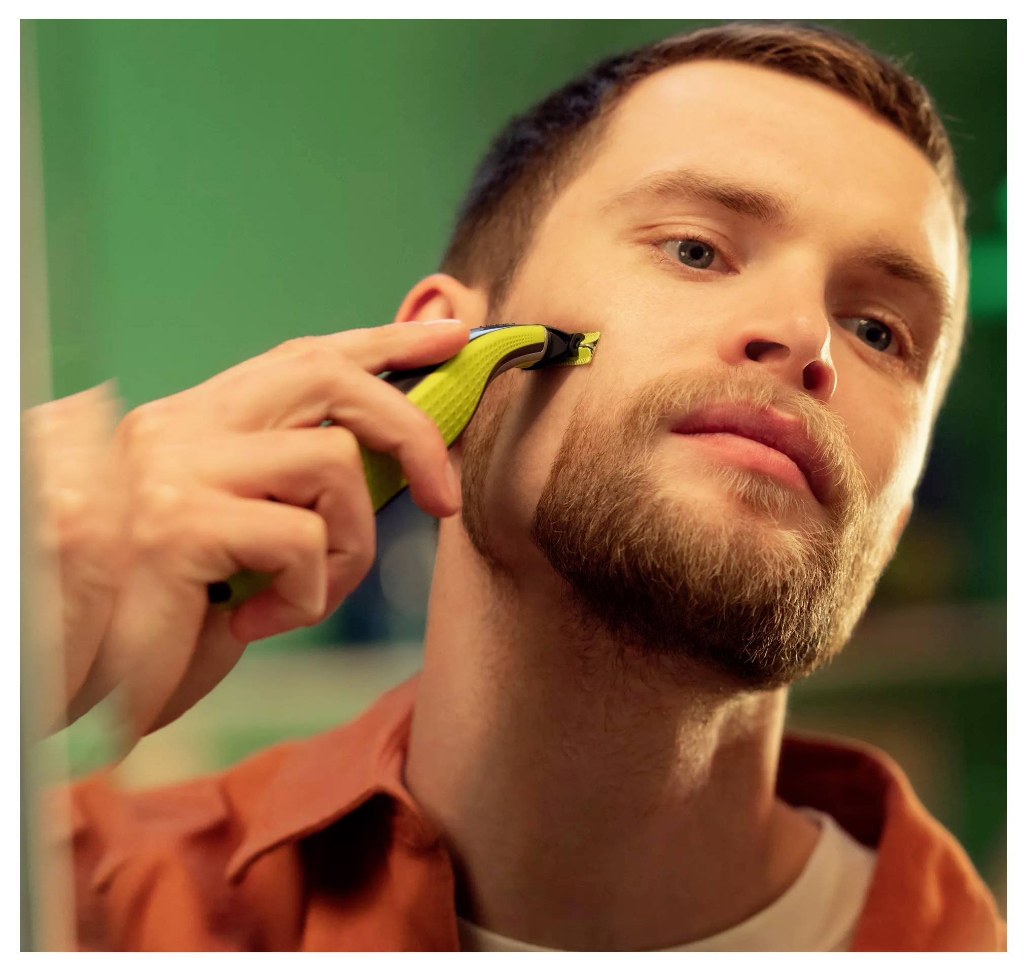L'homme se rase la barbe avec un trimmer électrique, gros plan du rasage du visage.