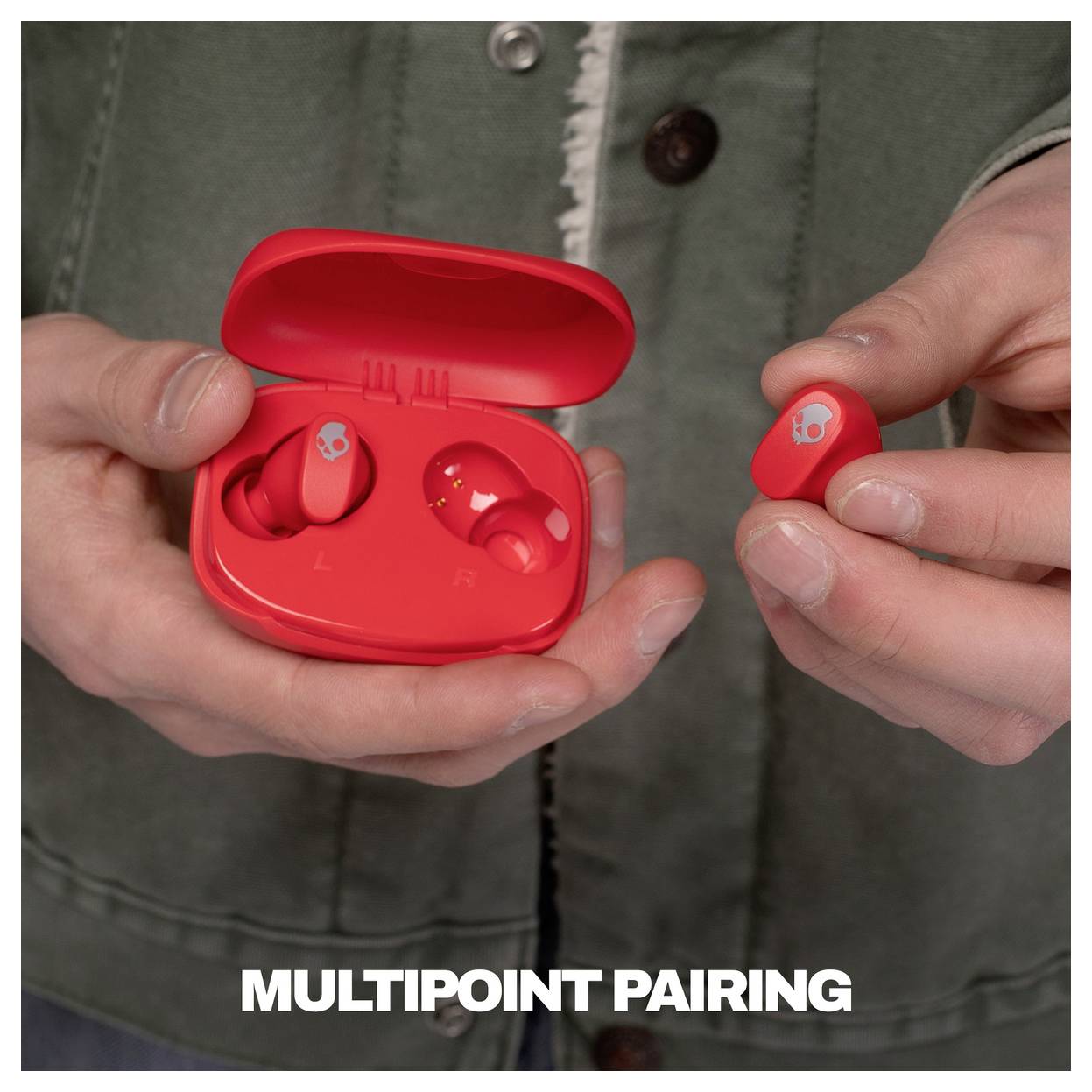 Les mains tenant des écouteurs sans fil rouges et leur étui de charge, accompagnés de la légende « APPAIRAGE MULTIPOINT ».