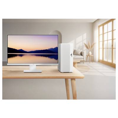 Moniteur de bureau et tour informatique sur une table en bois dans un salon lumineux, avec un fond d'écran de coucher de soleil calme sur un lac.