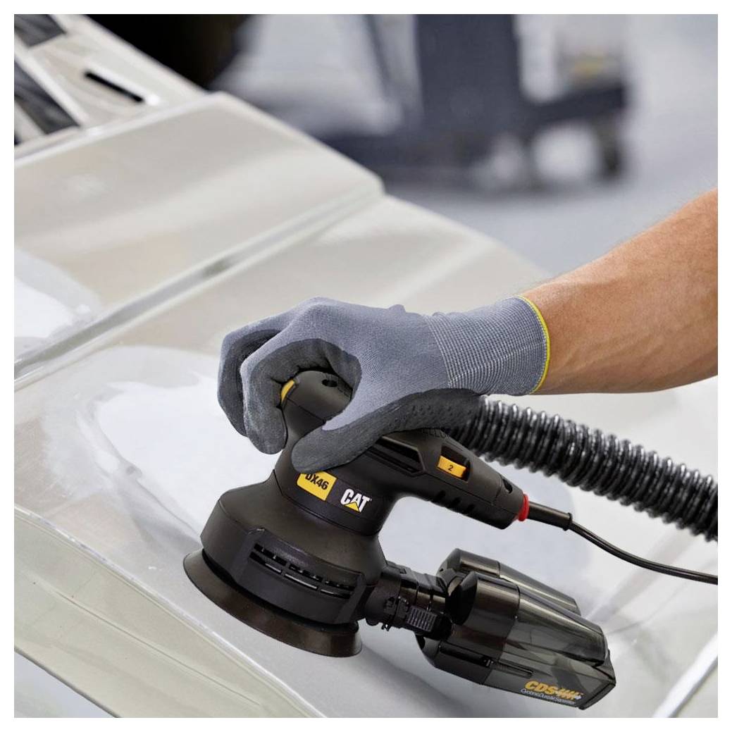 Main gantée utilisant une ponceuse/polisseuse électrique CAT sur un panneau de carrosserie automobile, probablement pour la réparation automobile ou la finition.