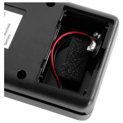 Gros plan d'un compartiment de dispositif en plastique noir montrant un fil rouge connecté à une batterie ou une pince d'alimentation à l'intérieur d'un boîtier ouvert.