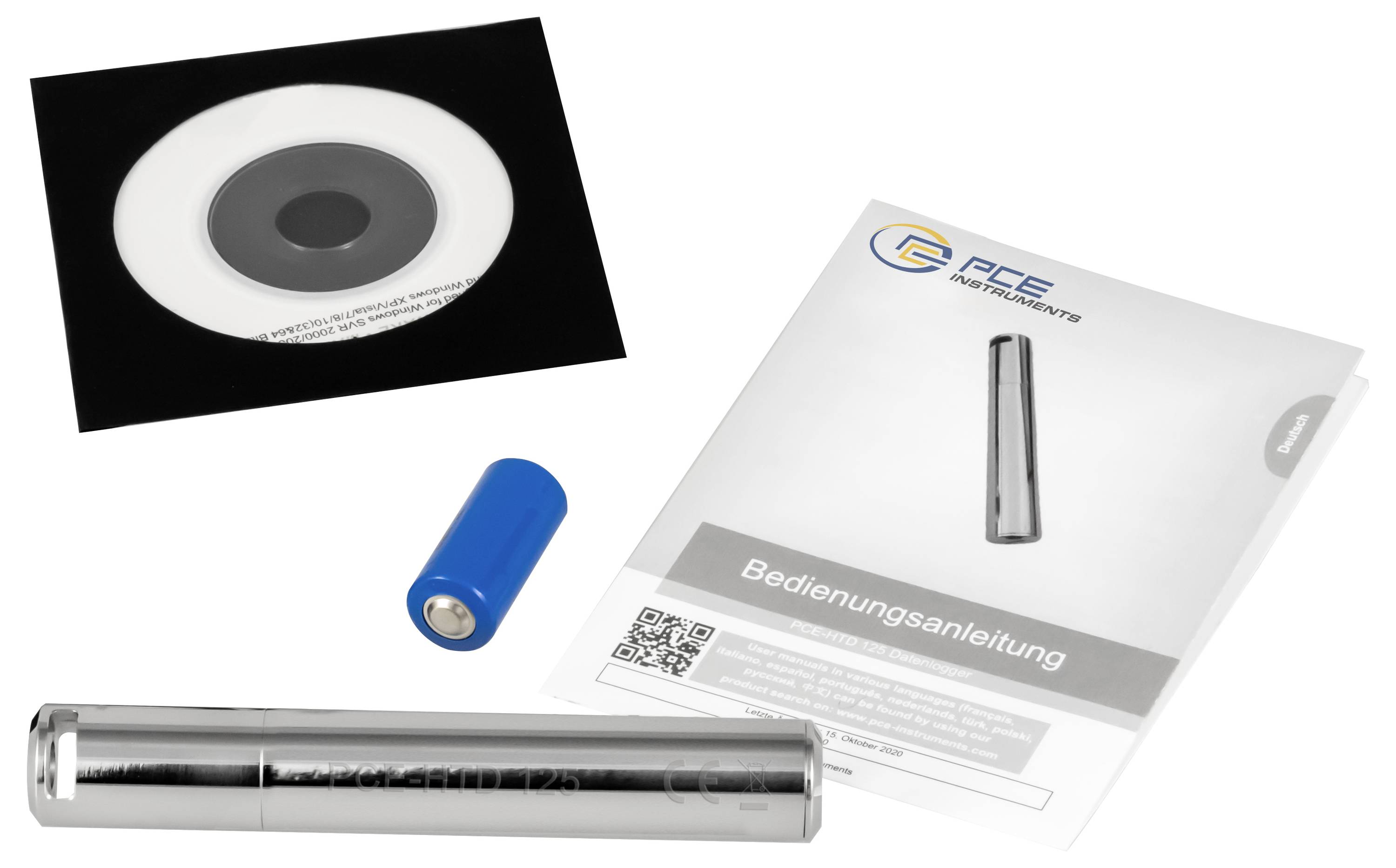 Contenu de l'emballage du produit : un disque noir et blanc, une batterie bleue, un dispositif cylindrique en acier inoxydable, et un manuel d'instructions « Bedienungsanleitung ».