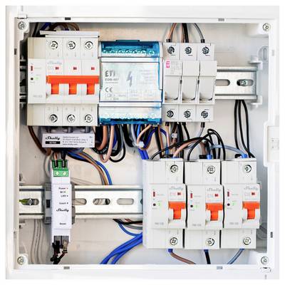 Panneau disjoncteur électrique ouvert avec plusieurs disjoncteurs modulaires, modules de relais et câblage montés sur rails DIN.