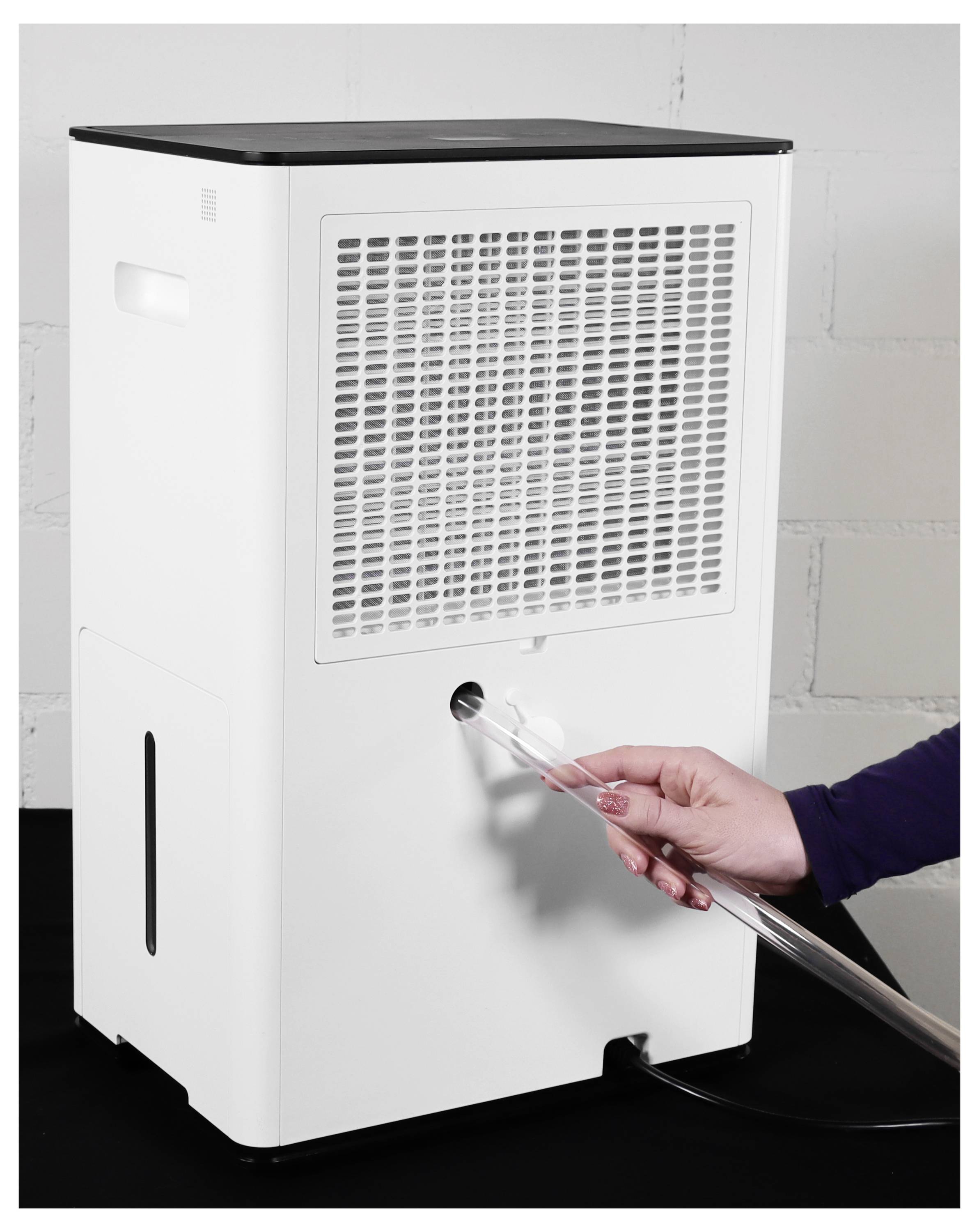 Une main connecte un tube transparent à un port avant d'un appareil blanc ressemblant à un humidificateur ou une machine similaire.