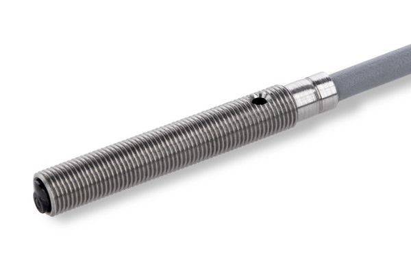 Gros plan d'une sonde de capteur métallique filetée attachée à un câble gris sur un fond blanc.
