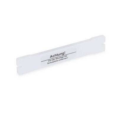 Bande de plastique blanc avec étiquette d'avertissement en français : « Attention ! Retirer le film de protection avant l'assemblage ! » sur un fond uni.