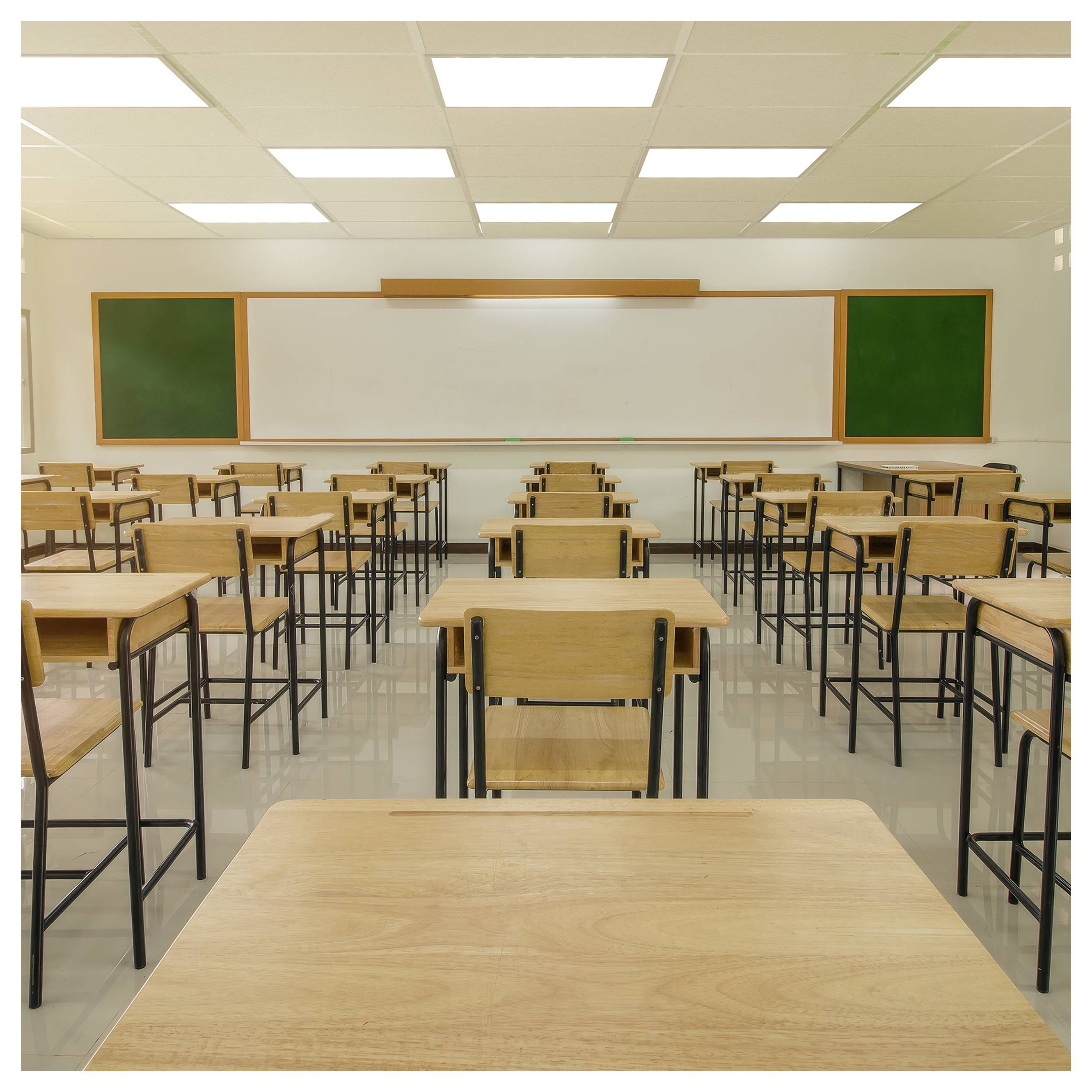 Salle de classe vide avec des rangées de pupitres et de chaises en bois faisant face à un tableau blanc et des tableaux noirs verts sous des lumières brillantes au plafond.