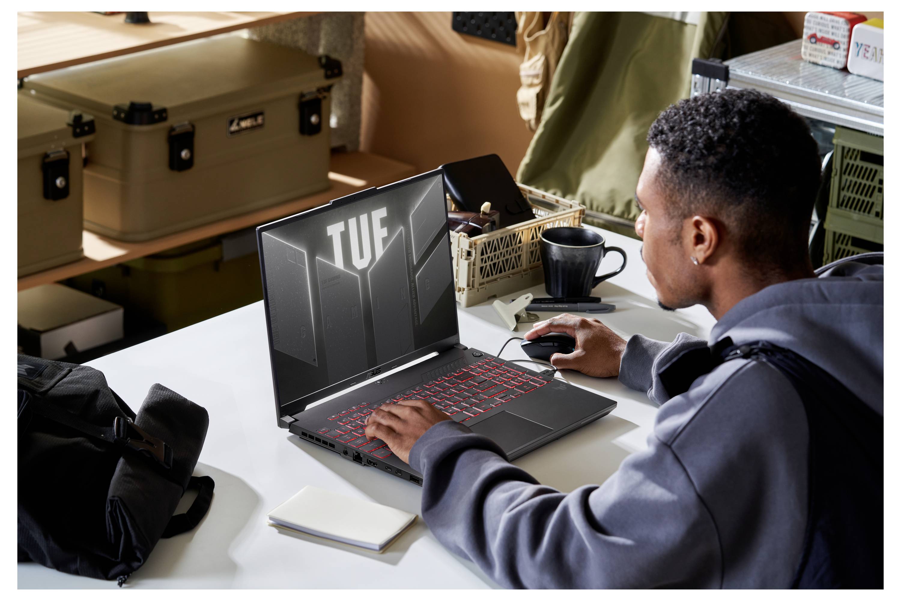 # Traduction vers le français<br><br>Personne utilisant un ordinateur portable à un bureau ; l'écran affiche la marque « TUF » tandis qu'elle travaille avec une souris dans un environnement de bureau.