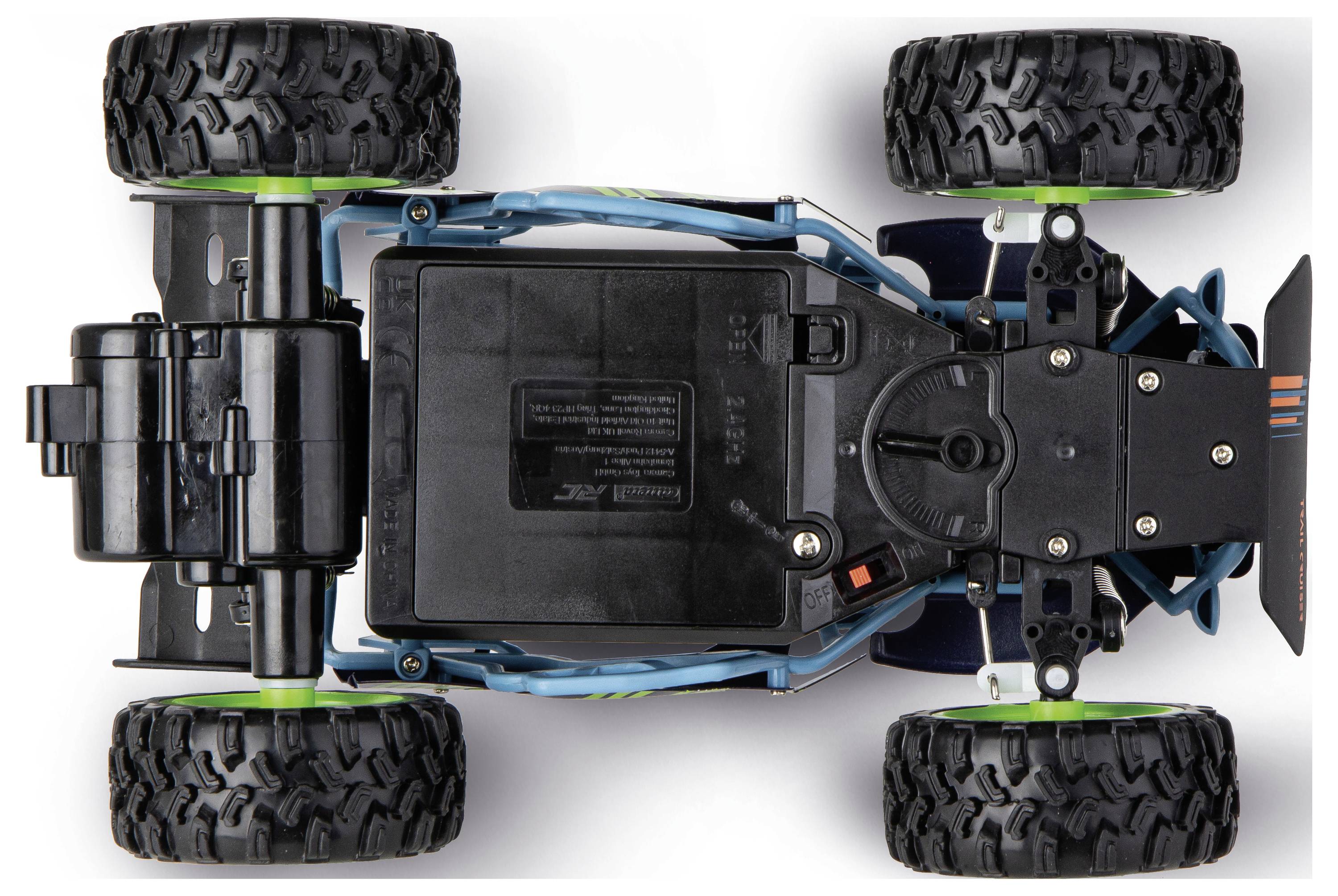 Vue de dessus d'un châssis de camion radiocommandé tout-terrain avec quatre gros pneus et des composants de batterie et de moteur exposés.