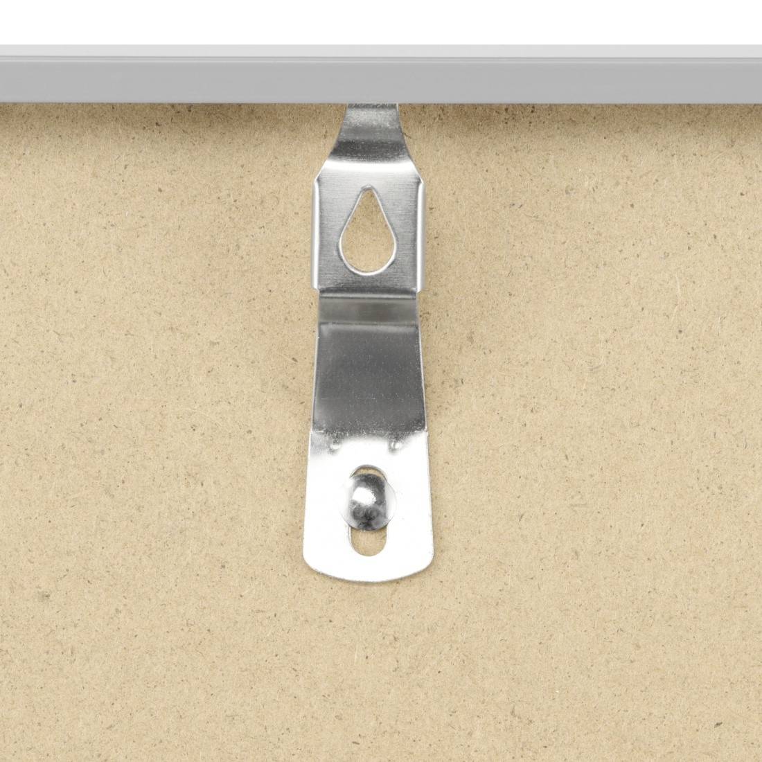 Gros plan d'un support métallique suspendu ou d'un accroche-tableau centré sur une surface de mur beige.