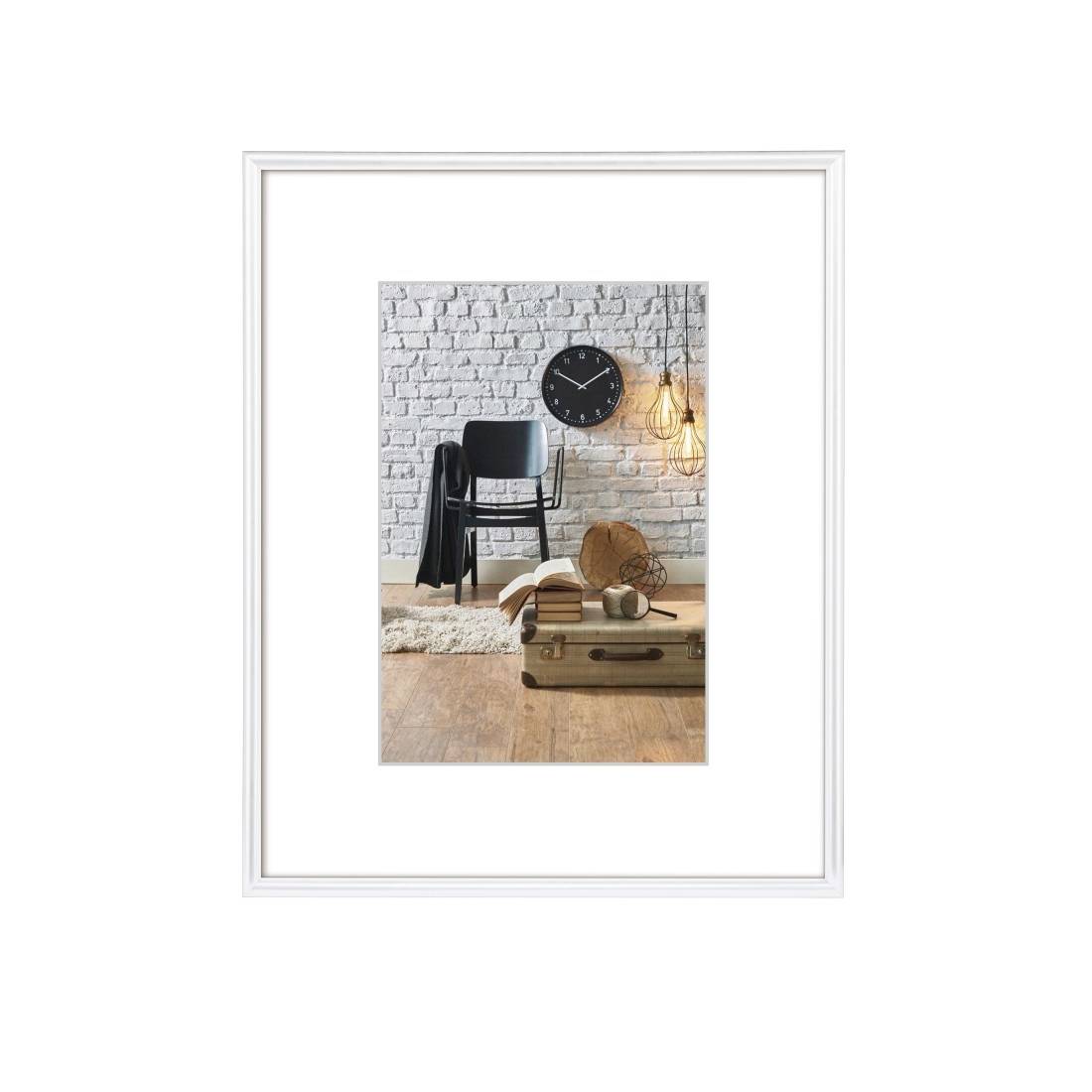 Photo intérieure encadrée d'une chaise à côté d'une horloge murale en briques, une lampe suspendue, des livres et une valise sur un plancher en bois.