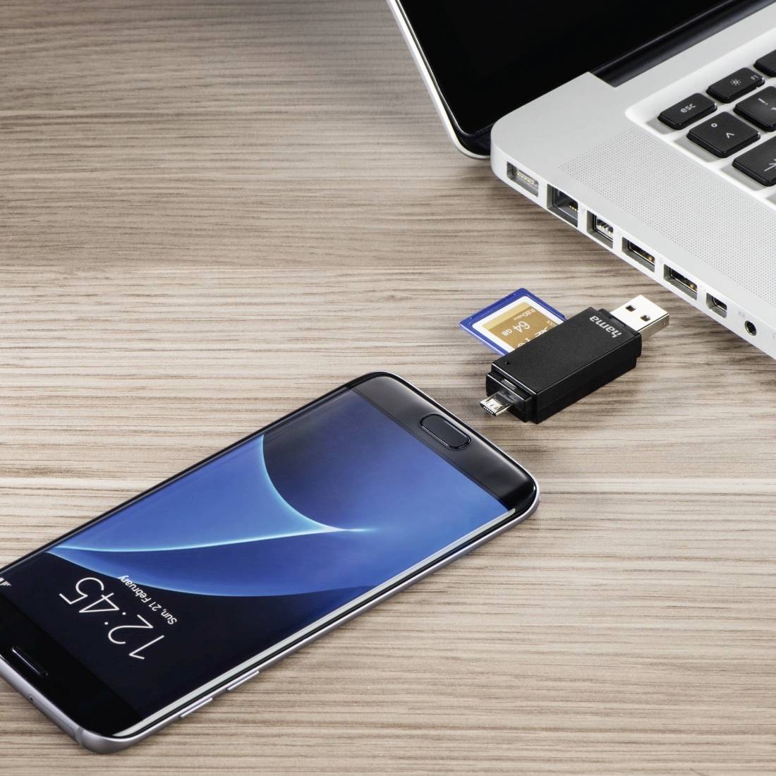 Téléphone intelligent, clé USB et carte mémoire à côté d'un ordinateur portable, suggérant un transfert de fichiers ou une sauvegarde d'appareil.