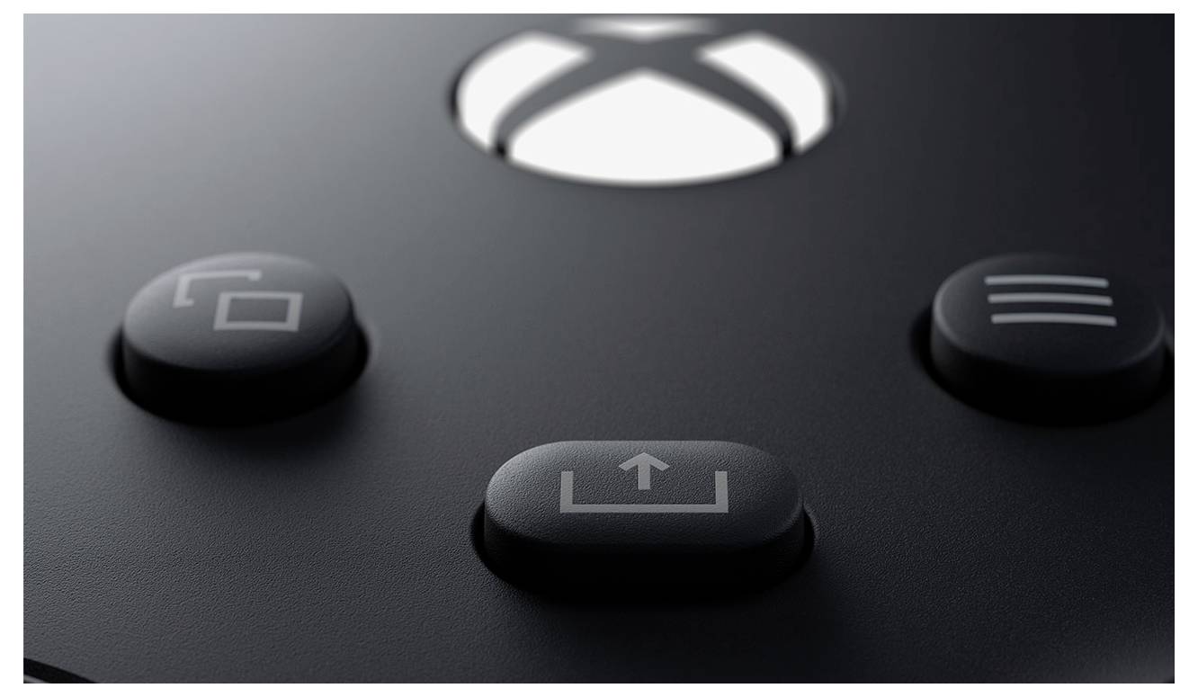Gros plan de trois boutons de manette Xbox noirs, incluant un bouton de partage central avec une icône de téléchargement, sur une surface sombre mate.