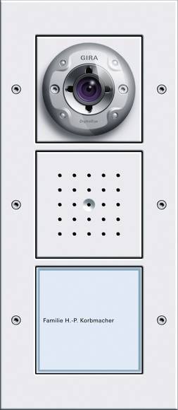 Panneau interphone avec un objectif de caméra en haut, une grille de haut-parleur au milieu et une plaque nominative en bas portant l'inscription « Familie H.-P. Korbmacher ».