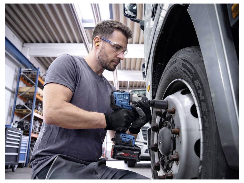 Mécanicien utilisant une boulonneuse à choc sans fil pour serrer les écrous de roue sur une roue de camion dans un atelier.