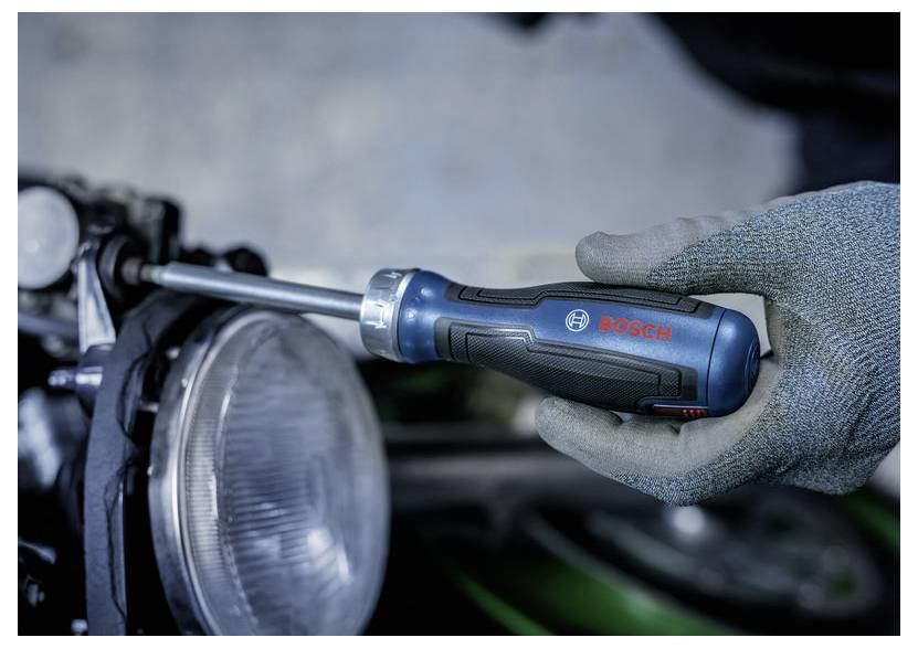 Main gantée serrant un ensemble de phare automobile avec un tournevis Bosch.