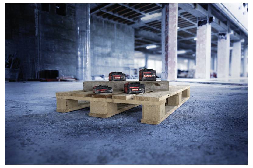 Trois batteries d'outils électriques sans fil sur des palettes en bois dans un entrepôt inachevé ou sur un chantier de construction.