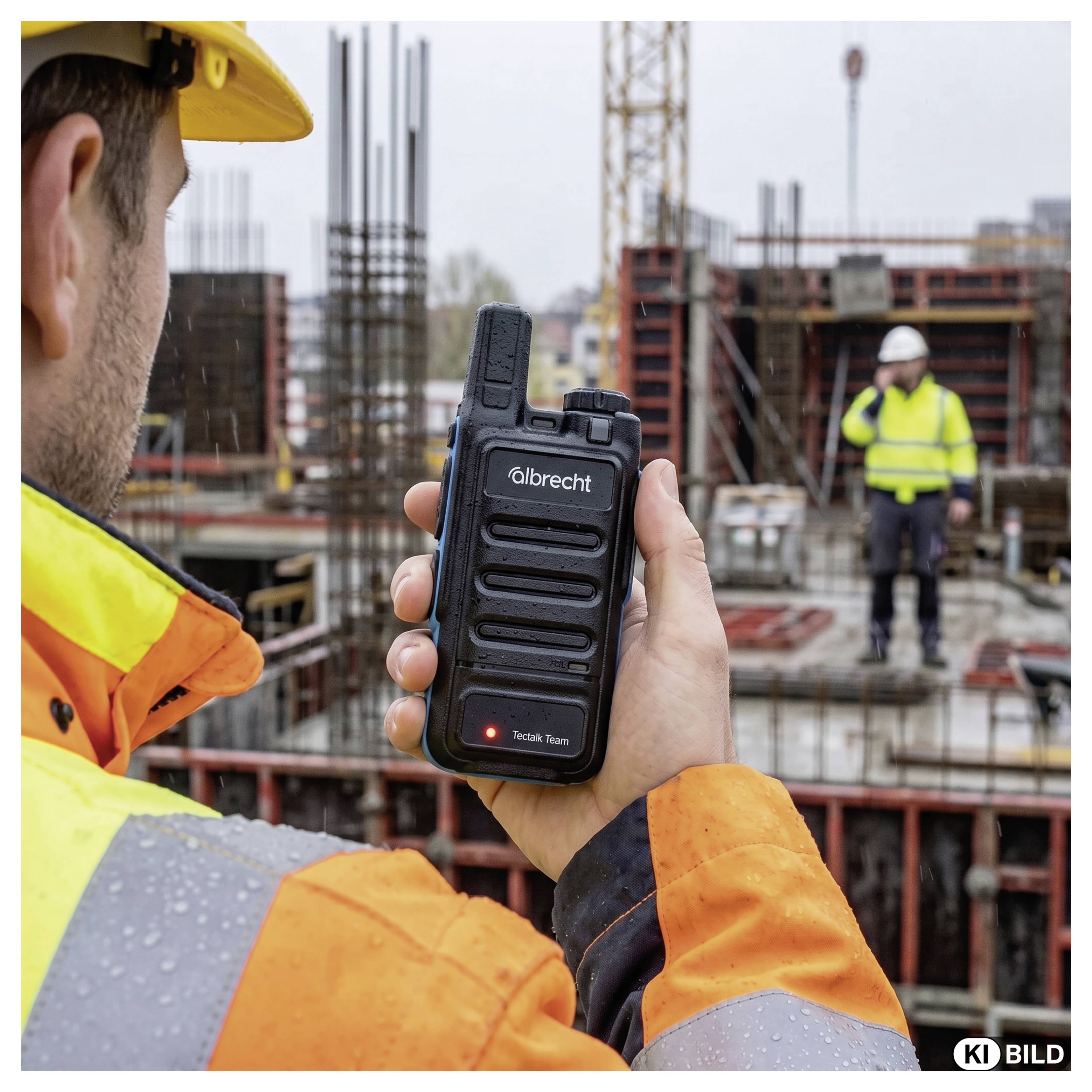 Ouvrier de la construction tenant une radio bidirectionnelle Albrecht sur un chantier, avec un collègue en équipement de sécurité visible en arrière-plan.