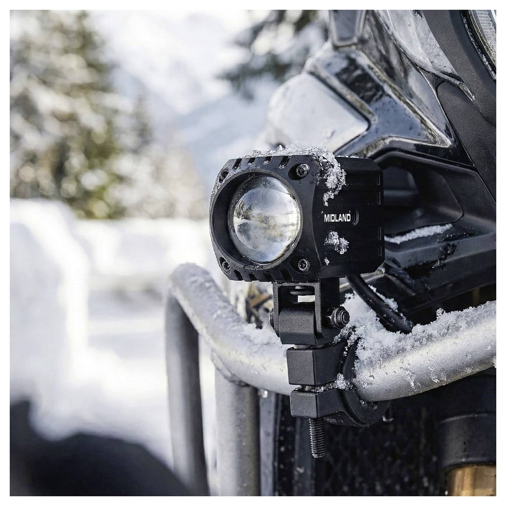 Gros plan d'un véhicule tout-terrain couvert de neige avec un projecteur auxiliaire Midland monté sur le pare-chocs avant.