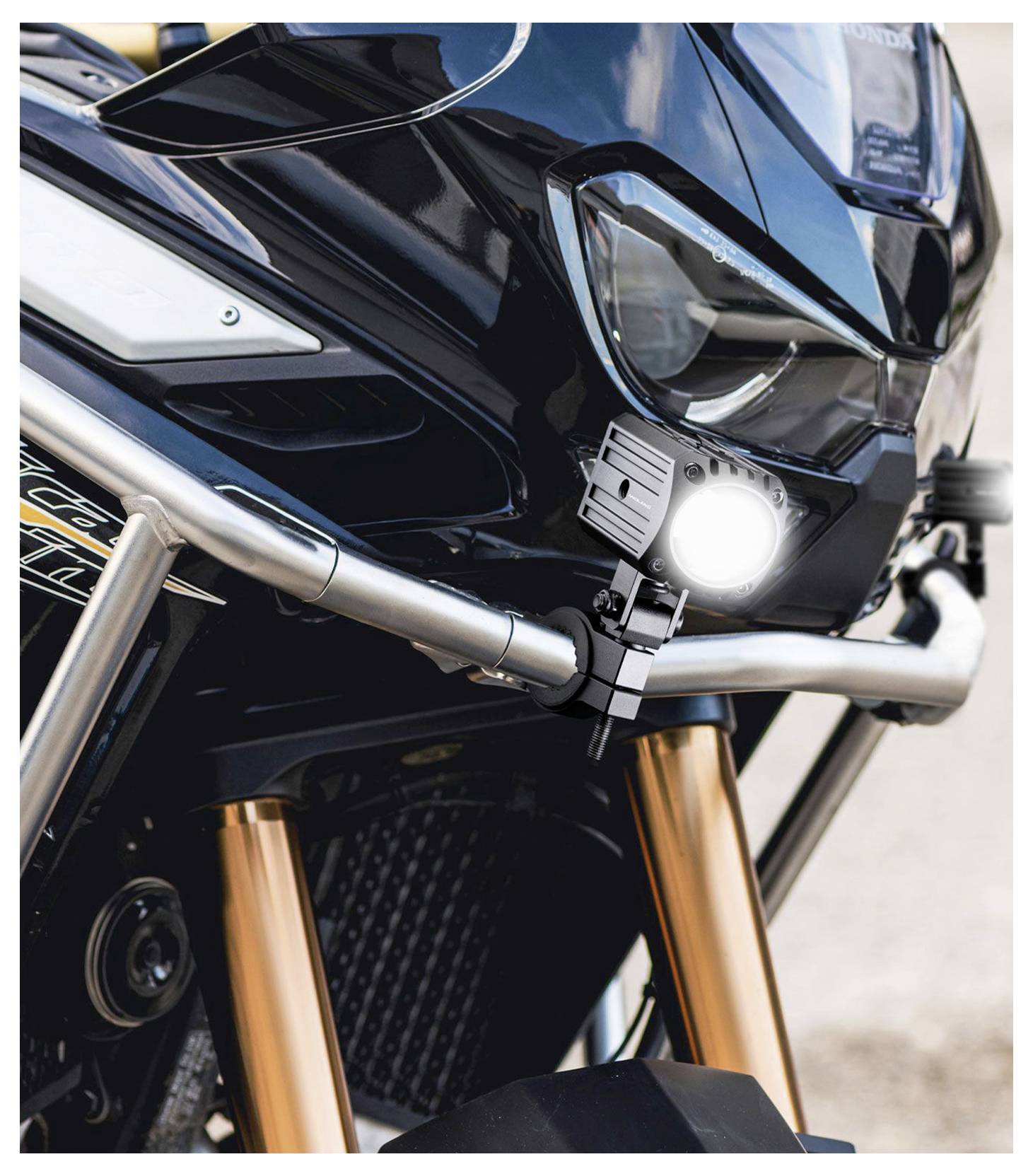 Gros plan d'une moto noire de face avec le phare LED allumé, une barre de protection argentée et des fourches dorées.