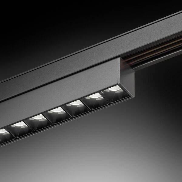 Fixture de rail lumineux noir moderne avec plusieurs lampes LED encastrées, présentée en gros plan sur un fond sombre.