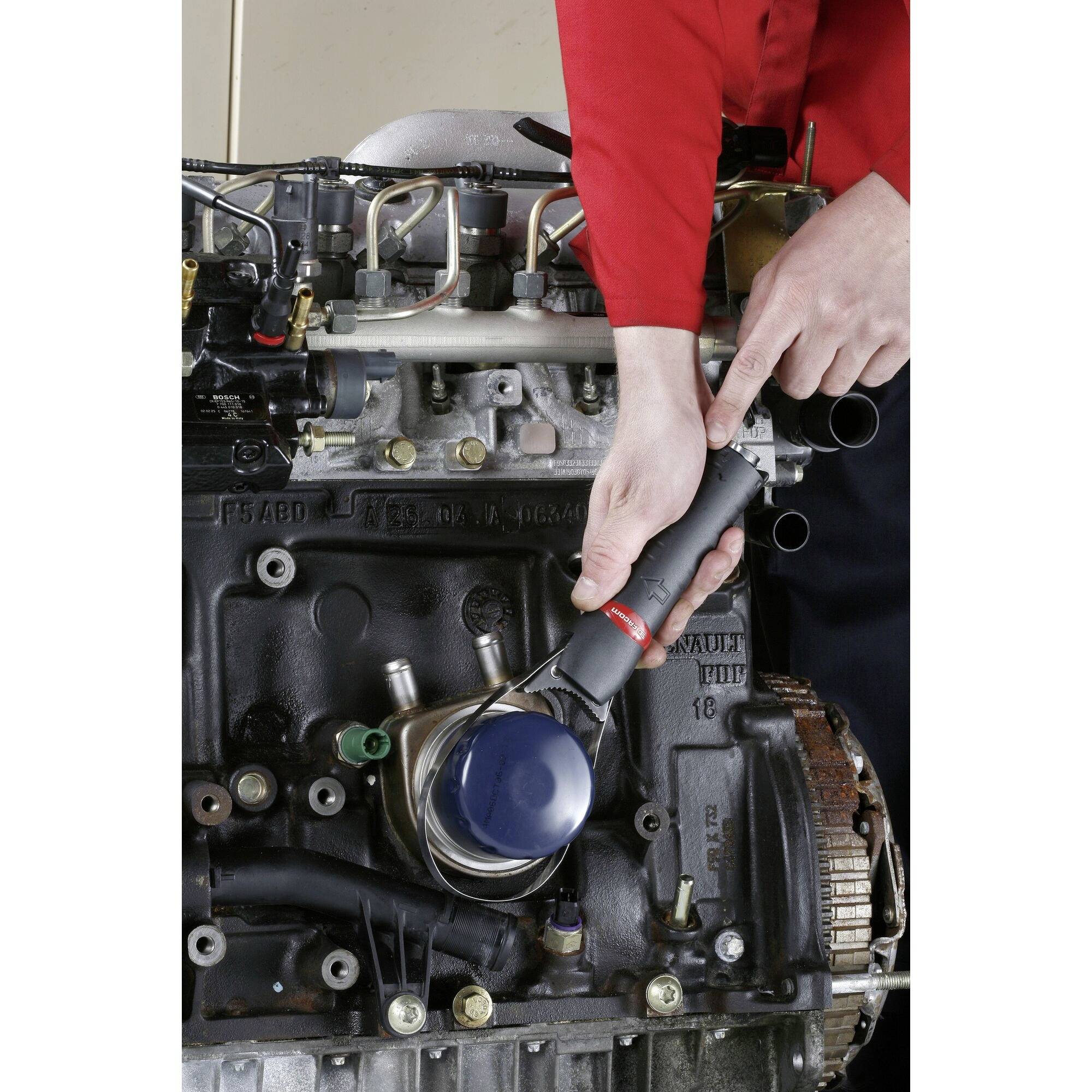 Une personne utilise une clé à cliquet sur un composant moteur, en serrant un boulon dans une vue rapprochée d'un moteur de voiture.