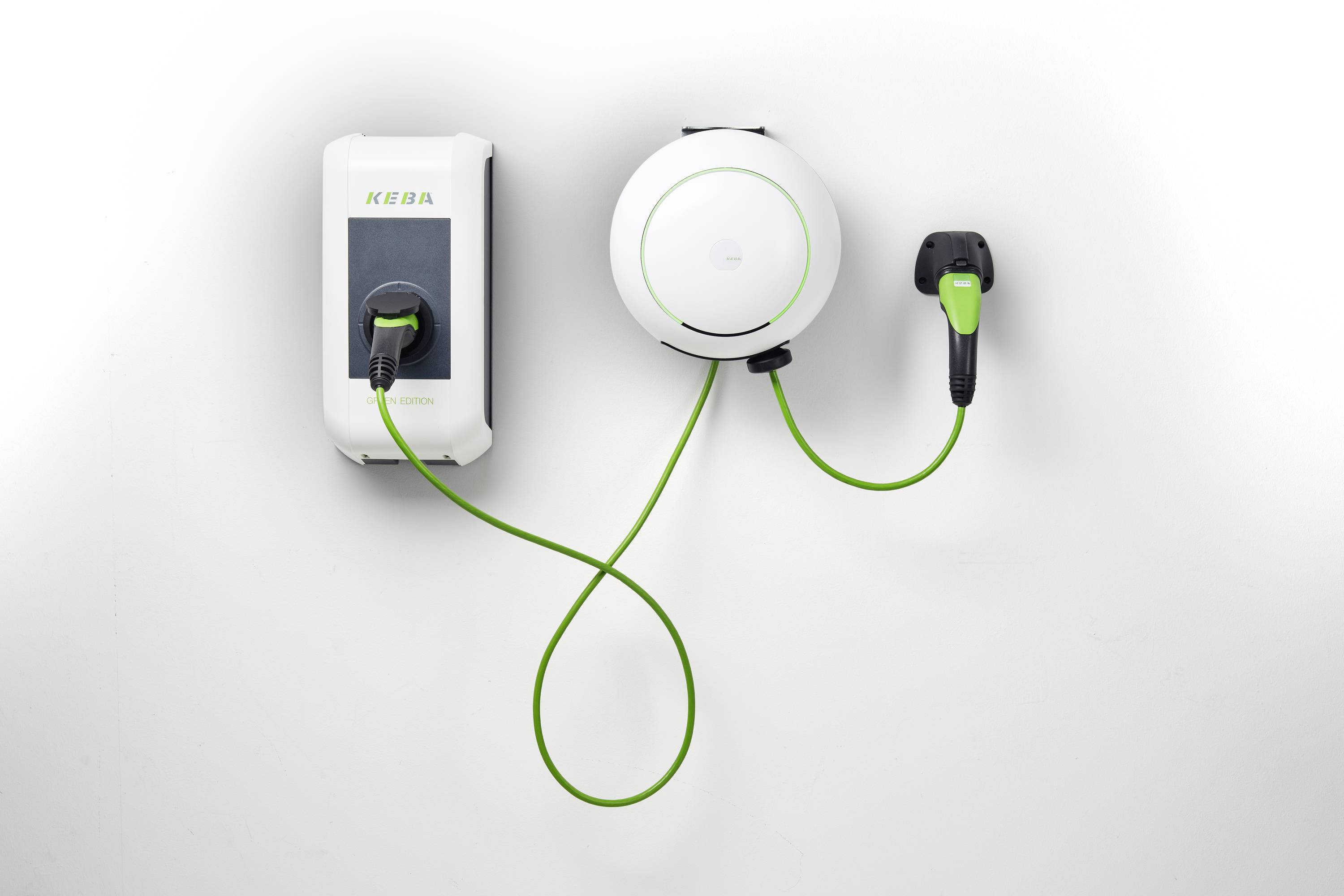 Chargeur de véhicule électrique mural avec une unité de charge KEBA, un enrouleur de câble circulaire et un câble de charge vert branché connecté à une prise murale.