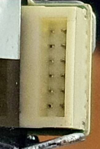 Gros plan d'un connecteur électrique rectangulaire beige avec des trous de broche, monté sur un fond sombre.