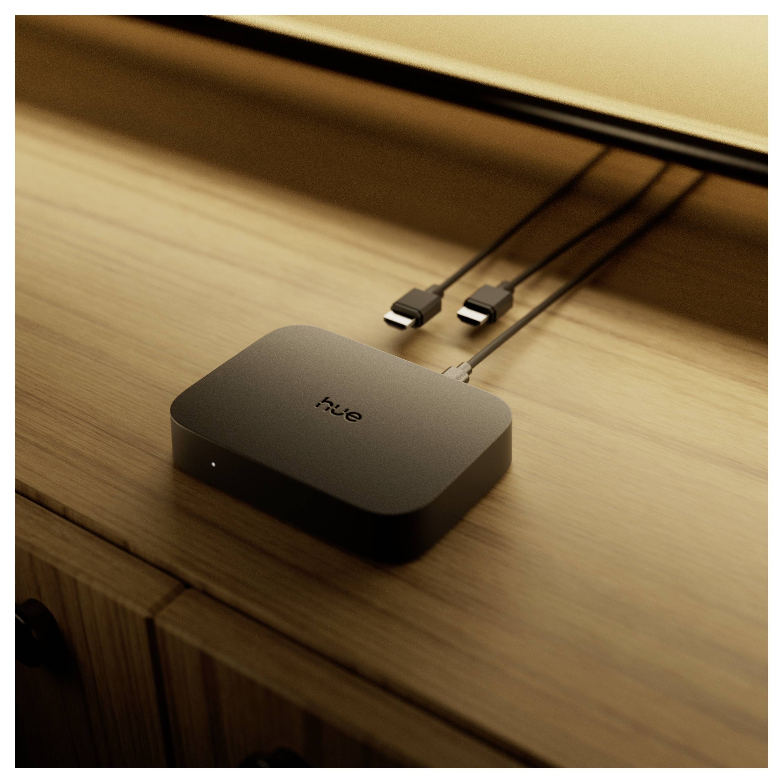 Concentrateur intelligent Black Hue sur une surface en bois, avec deux câbles connectés et une petite lumière indicatrice près du bord avant.