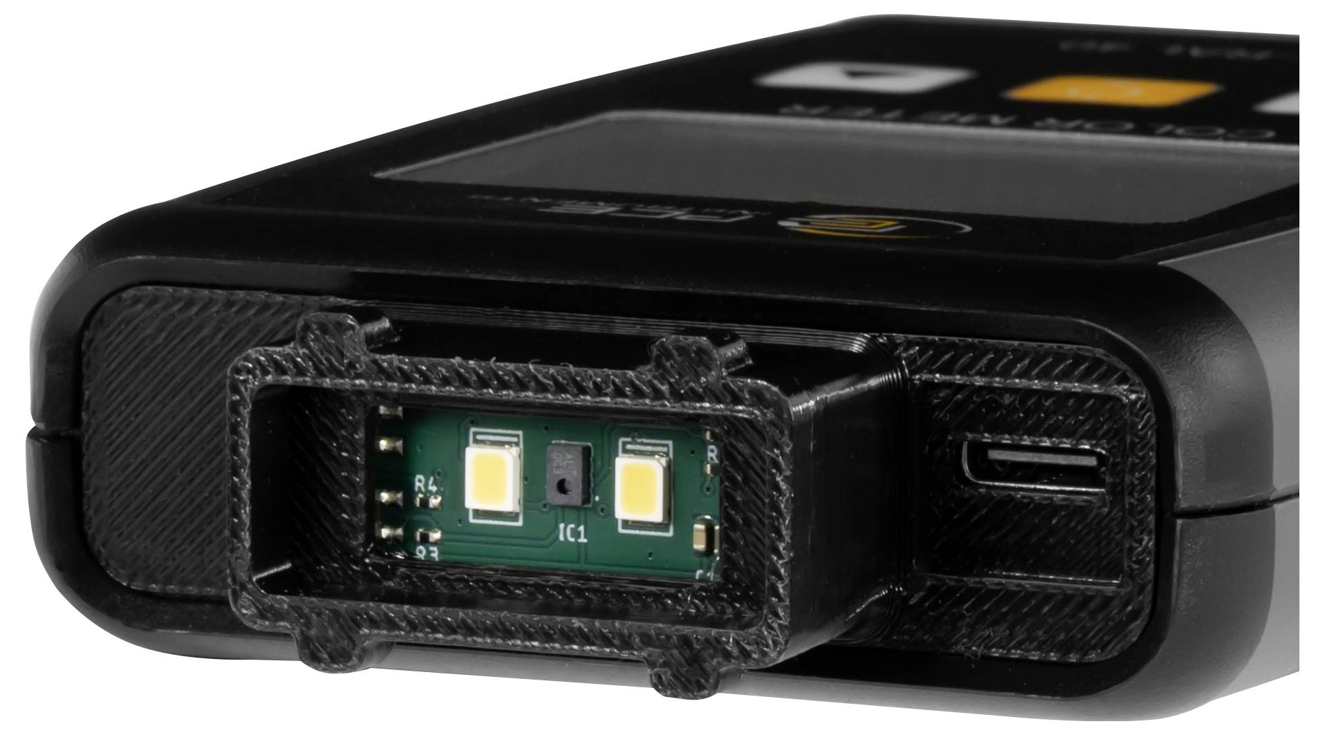 Gros plan d'un appareil électronique noir avec une petite carte de circuit intégrée exposée dans la fente frontale, montrant deux composants de type LED et des connecteurs latéraux.