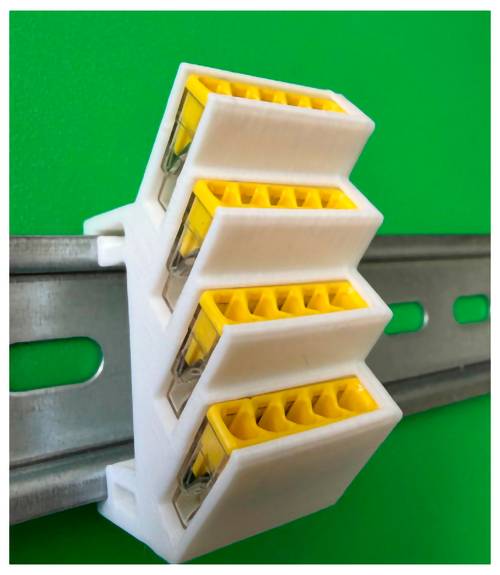 Gros plan d'un connecteur électrique blanc et jaune fixé sur un rail en métal gris sur un fond vert.