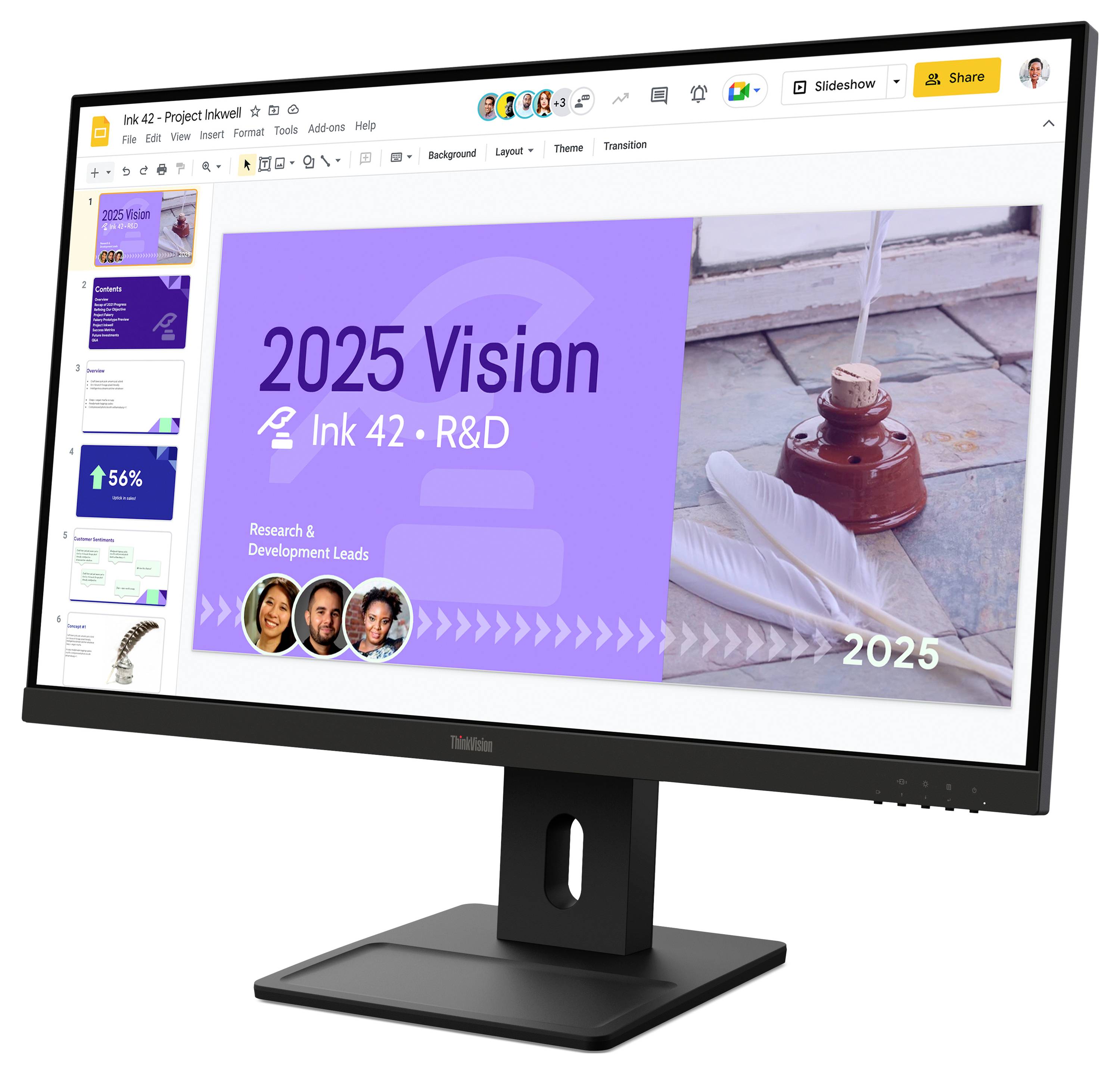 Un moniteur de bureau affiche une diapositive de présentation intitulée « Vision 2025 » pour la R&D d'Ink 42, avec un panneau violet, une photo à droite et une rangée de portraits d'équipe.