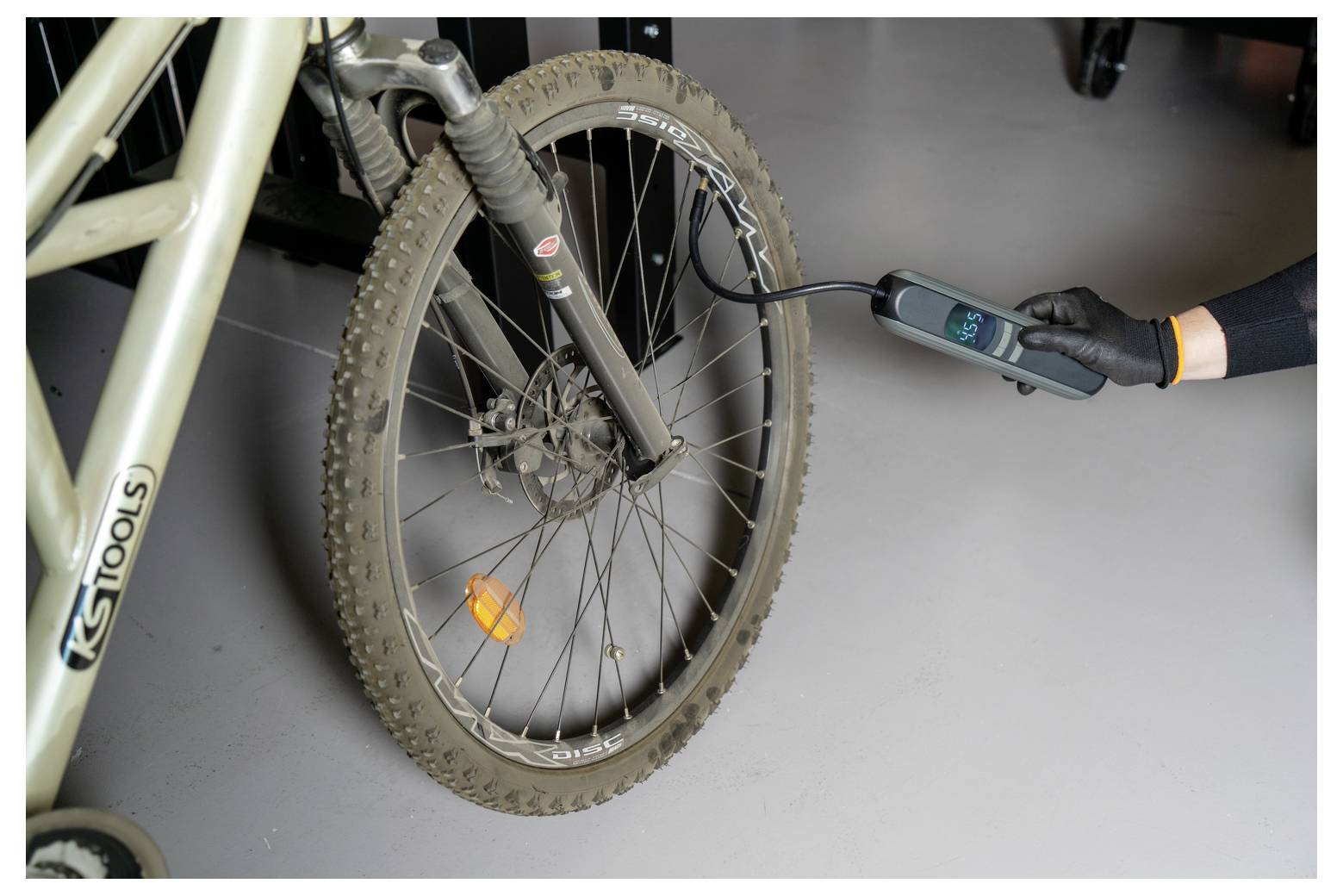 La main gantée utilise un manomètre numérique pour vérifier la pression d'un pneu de vélo de montagne.