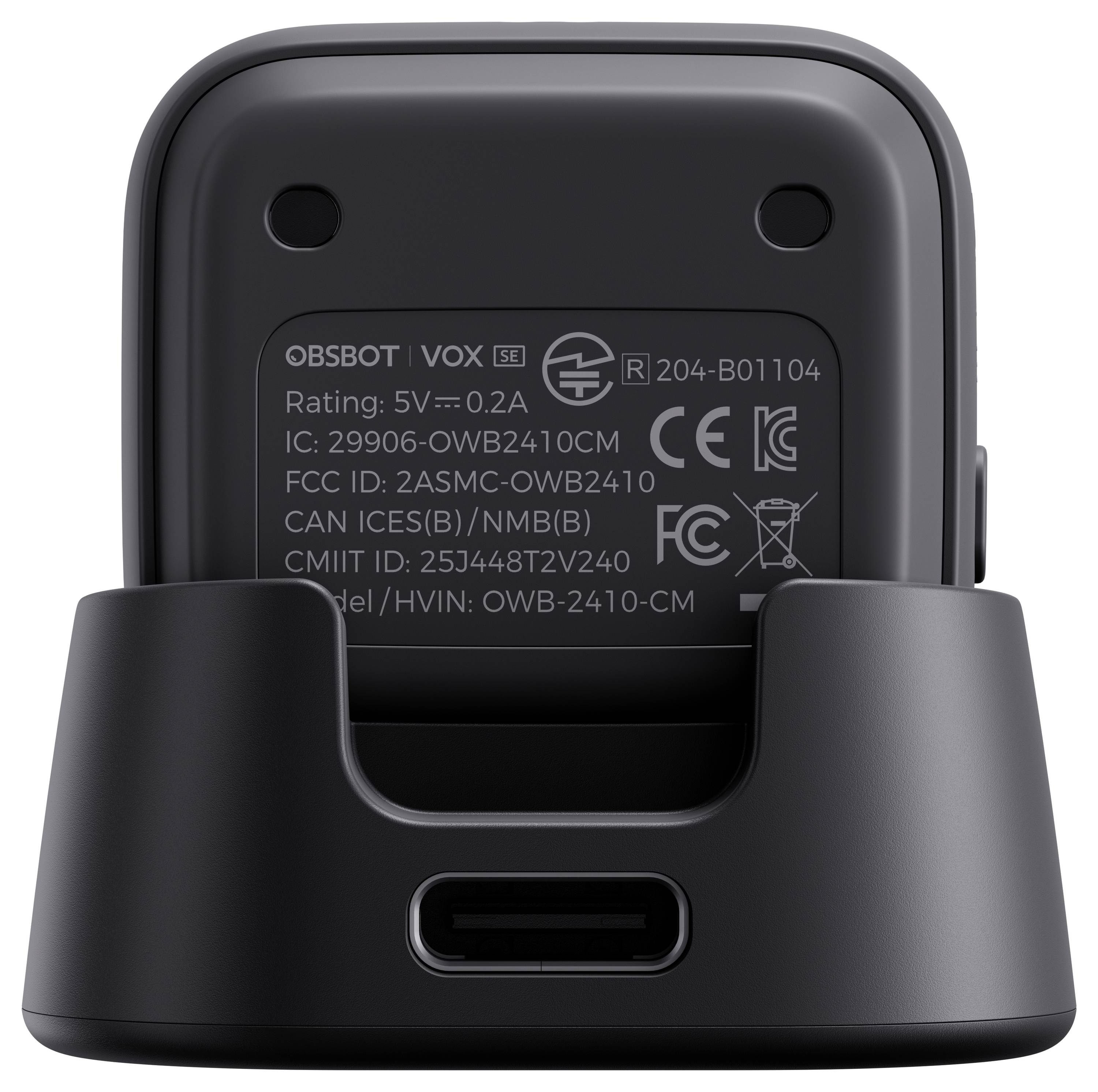Vue arrière d'un appareil OBSBOT VOX SE assis dans un socle de recharge, montrant les étiquettes réglementaires et un port de recharge USB-C.