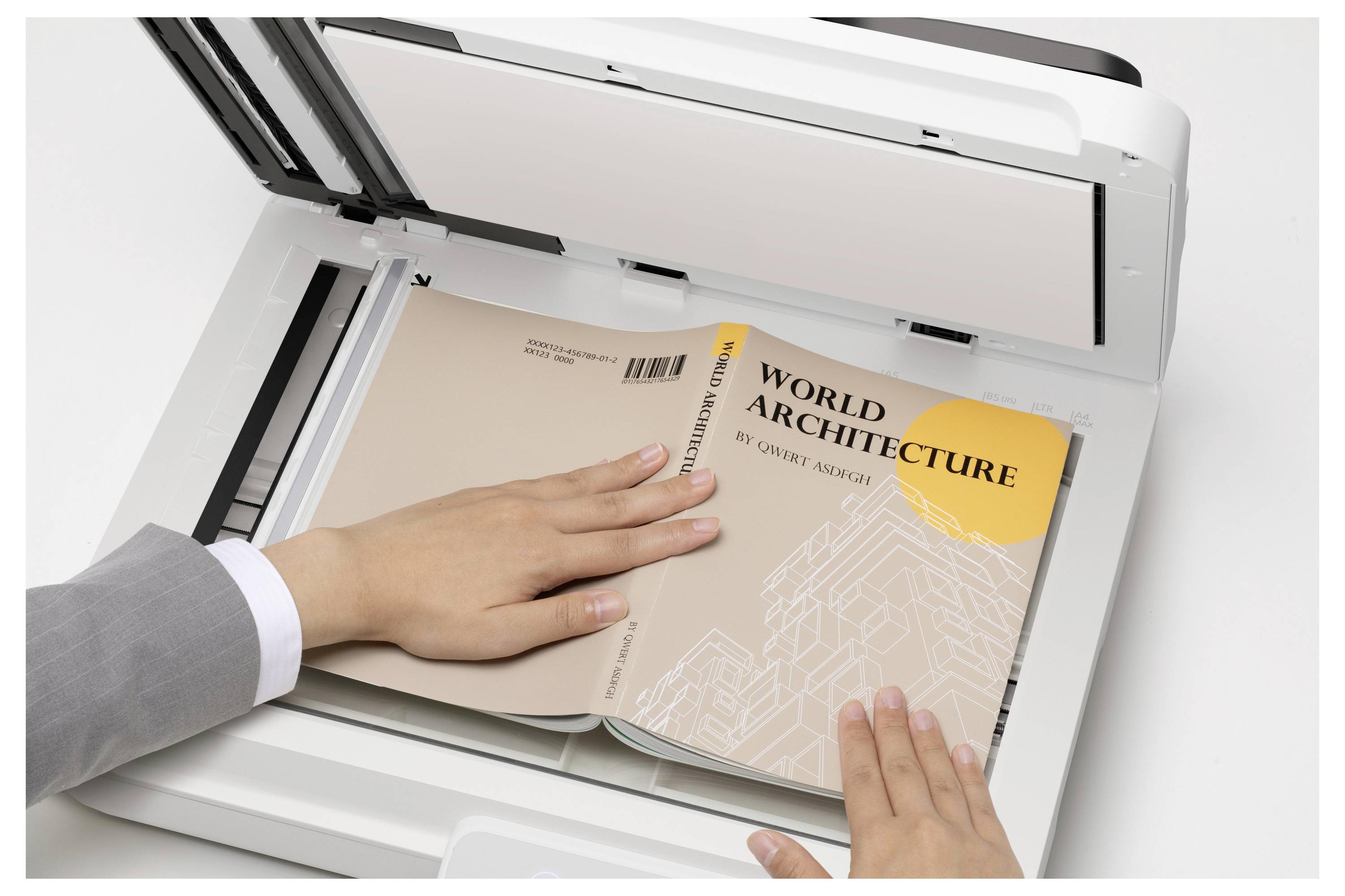 Les mains en train de scanner un livre intitulé « Architecture mondiale » sur un scanner à plat avec le couvercle ouvert.