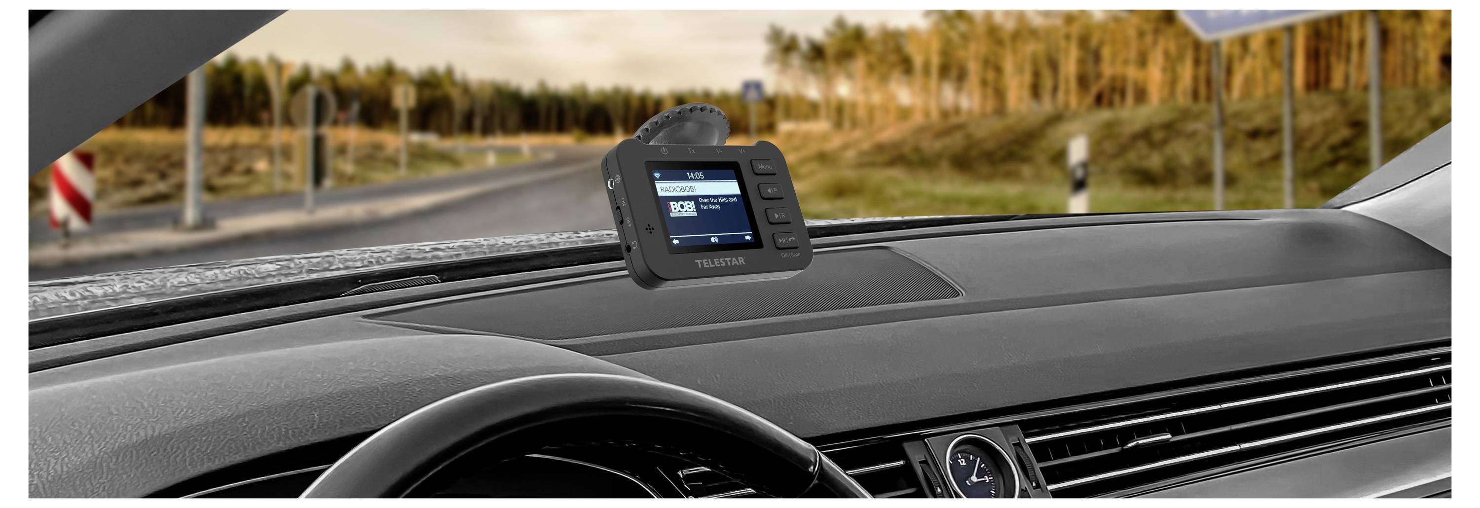 Appareil électronique monté au tableau de bord avec écran et boutons, probablement une caméra automobile ou une unité de navigation, positionnée sur le pare-brise au-dessus du tableau de bord pendant la conduite de jour.