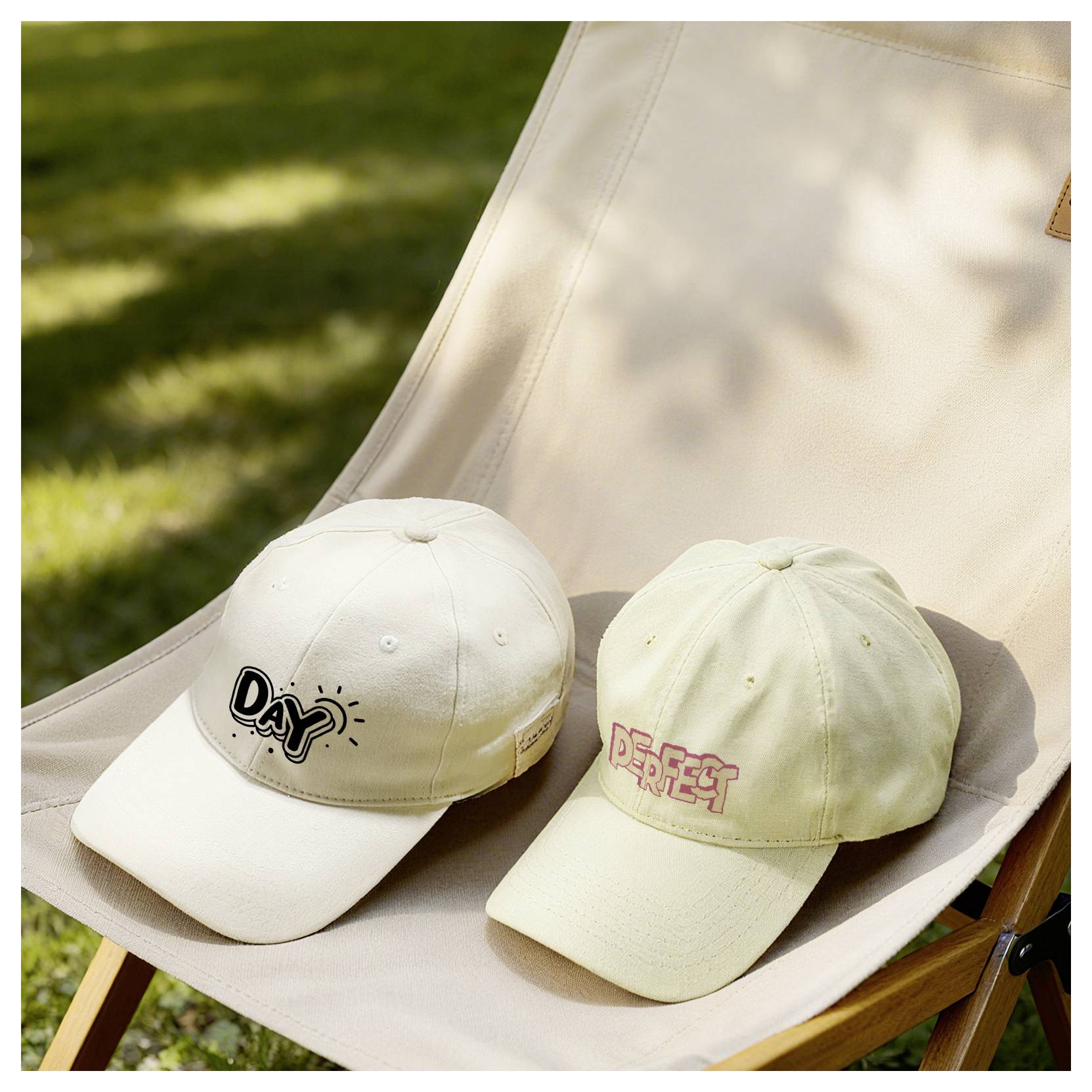 Deux casquettes de baseball beige sur une chaise longue à l'extérieur, l'une avec « Day » brodé sur l'avant et l'autre avec « Perfect ».