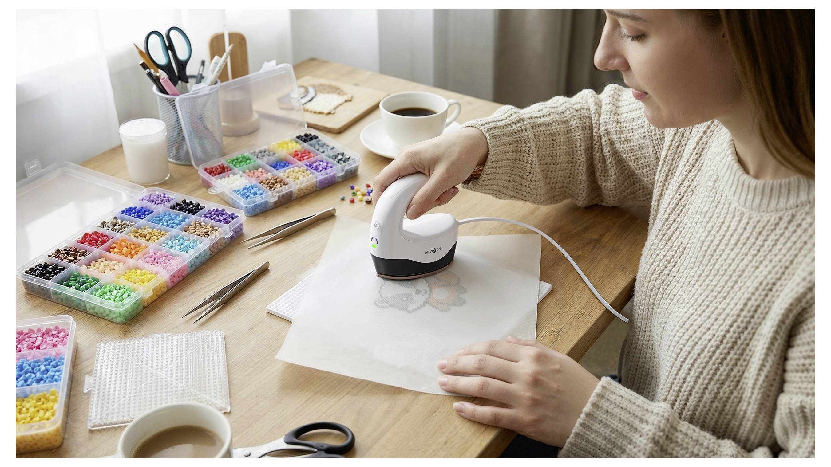 Une femme utilise un outil artisanal portatif pour presser un motif sur du papier à une table avec des perles colorées et des fournitures artistiques.
