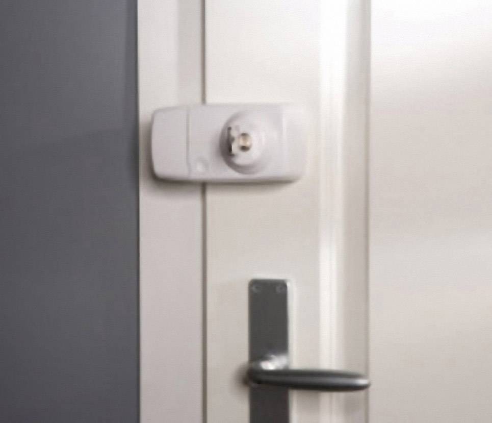 Porte avec une poignée argentée et une serrure électronique blanche au-dessus. Le mur à côté est gris foncé.