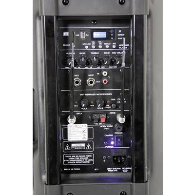 Gros plan d'un système de sonorisation. Montre différents boutons de commande et connexions, comprenant le volume du microphone, les réglages des basses et des aigus.