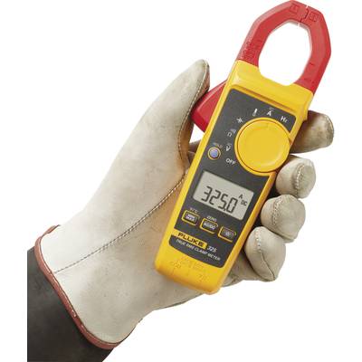 Appareil de mesure tenu dans une main gantée indiquant 3250 A de courant continu. L'appareil est jaune avec une pince rouge.