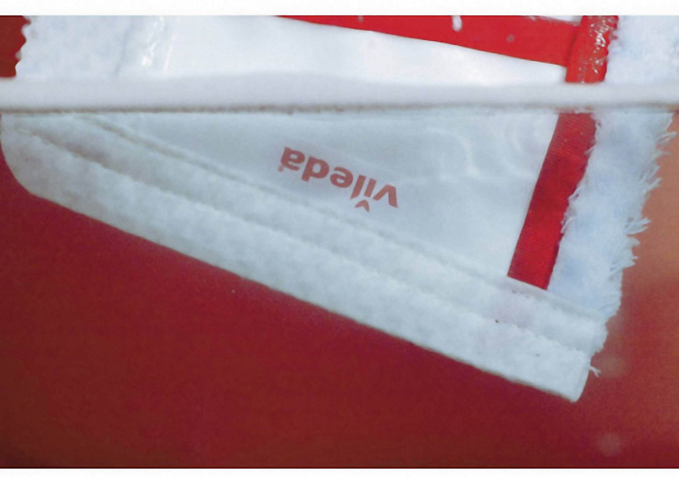 Un chiffon blanc et rouge Vileda en gros plan, partiellement trempé dans l'eau.